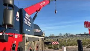 Red A-Lift crane truck with raised boom on a worksite under a blue sky