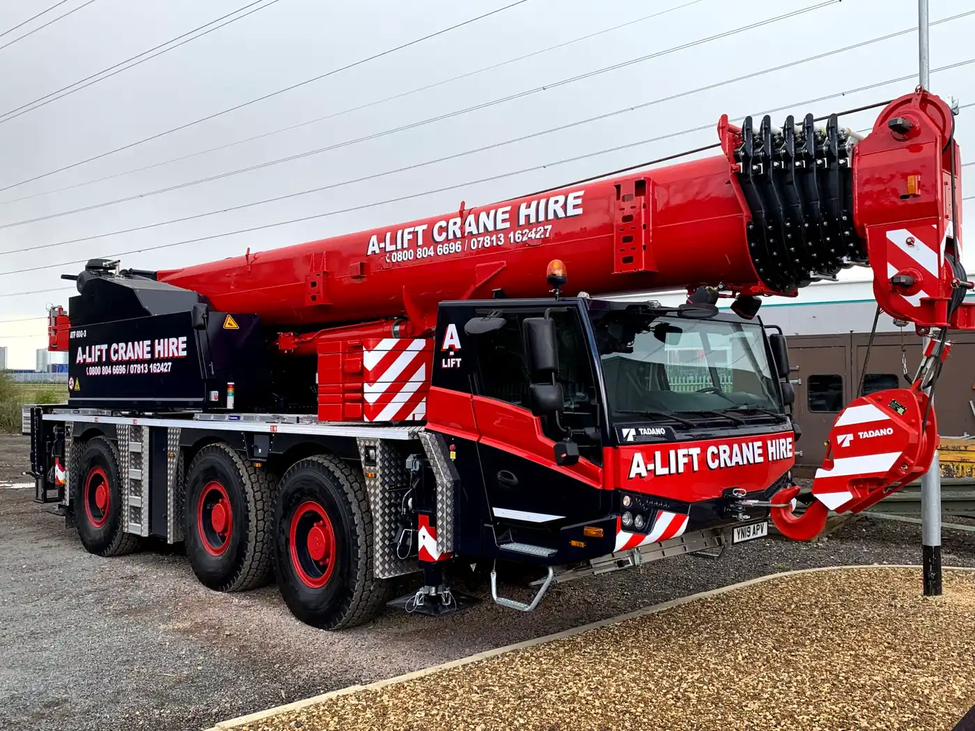 Red A-Lift Crane Hire mobile crane with extended boom and hook block outdoors
